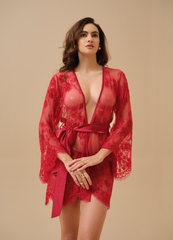 Woman wearing a red lace robe against a beige background
